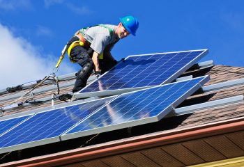 Man installing alternative energy photovoltaic solar panels on roof